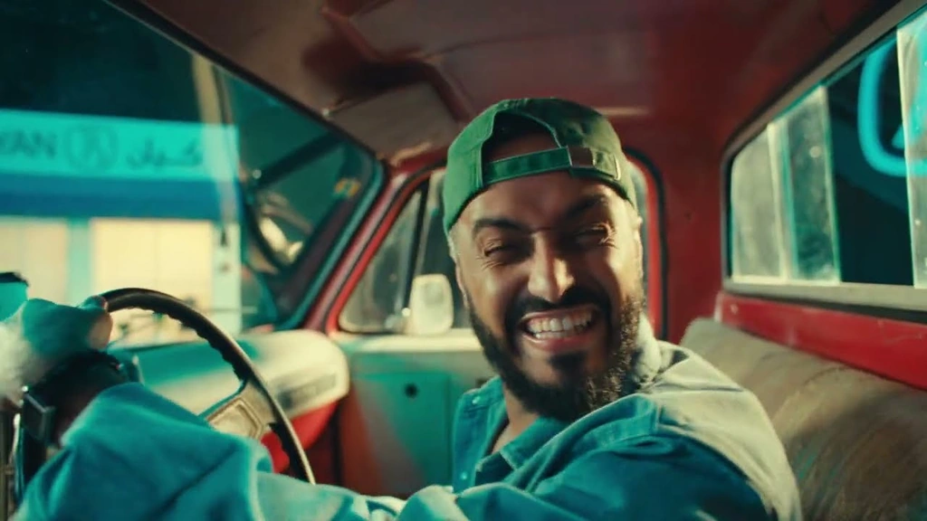 Tareq Al-Harbi smiles from the driver’s seat of a red car.