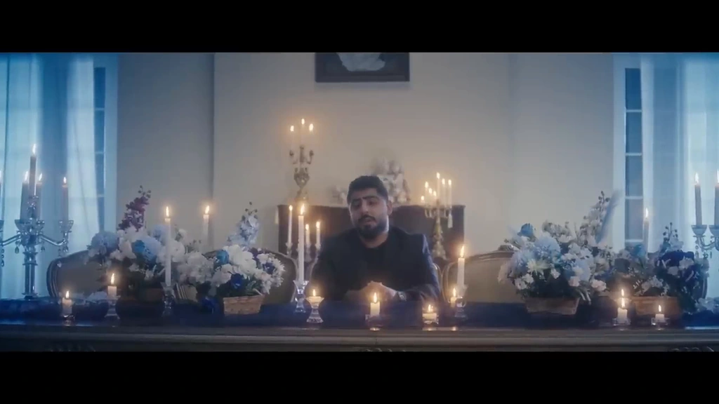 Akhras sits behind a table of flowers and candles in the blue-lit room.