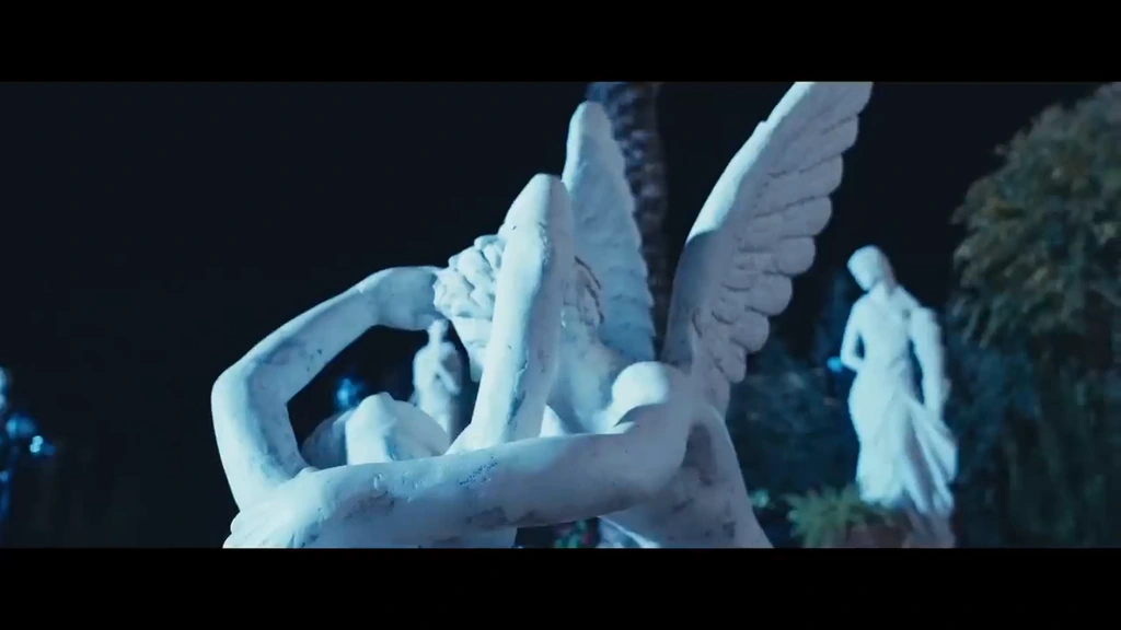 A winged garden sculpture illuminated in cool light.