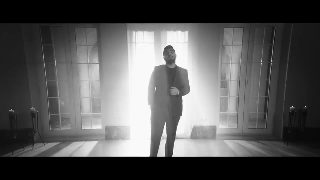 A full-length black-and-white portrait against a bright doorway.
