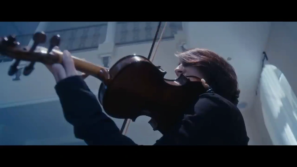 Close view of a violinist performing amid the cool-lit interior.