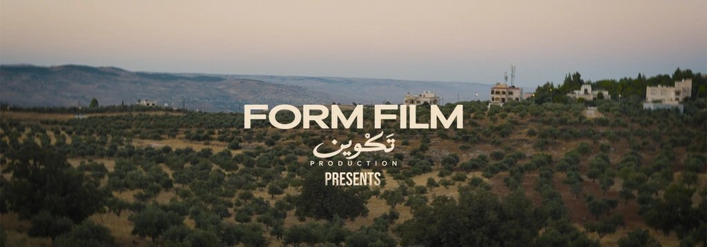 Opening production credits over olive groves and hillside buildings at dusk.