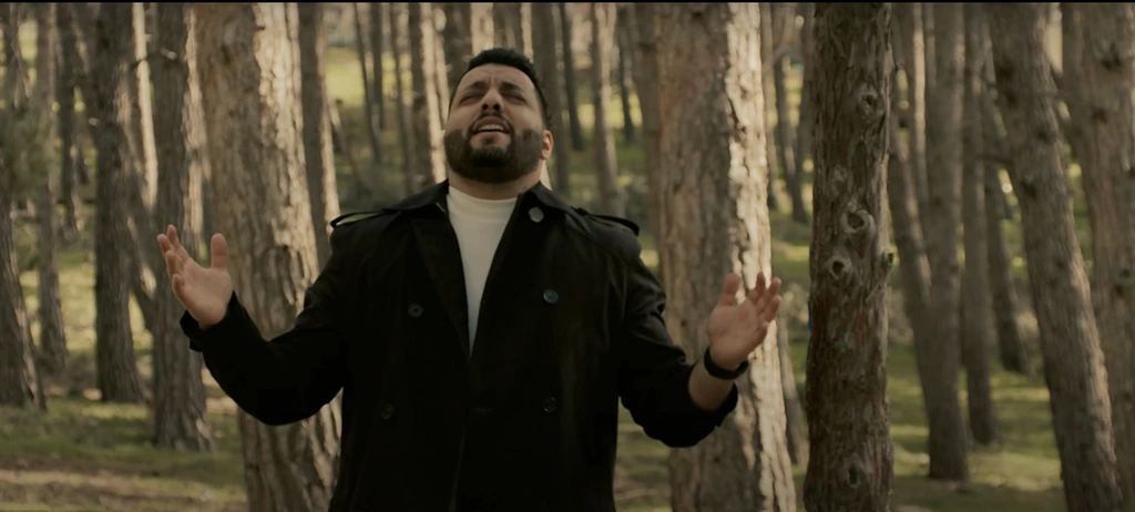 Ibrahem performs between the trunks of a sunlit forest.
