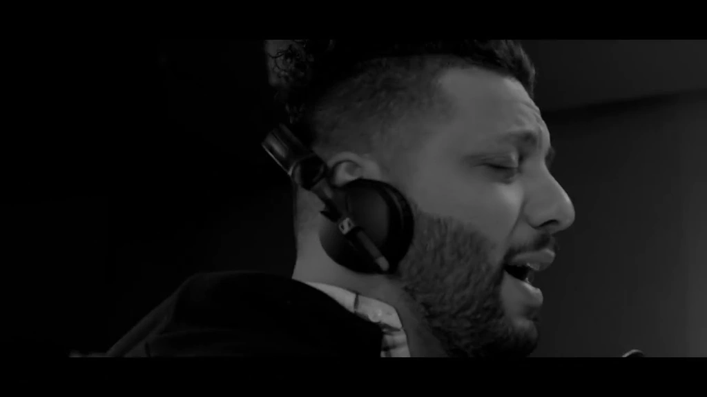 Ibrahem wears headphones in a monochrome recording-room close-up.
