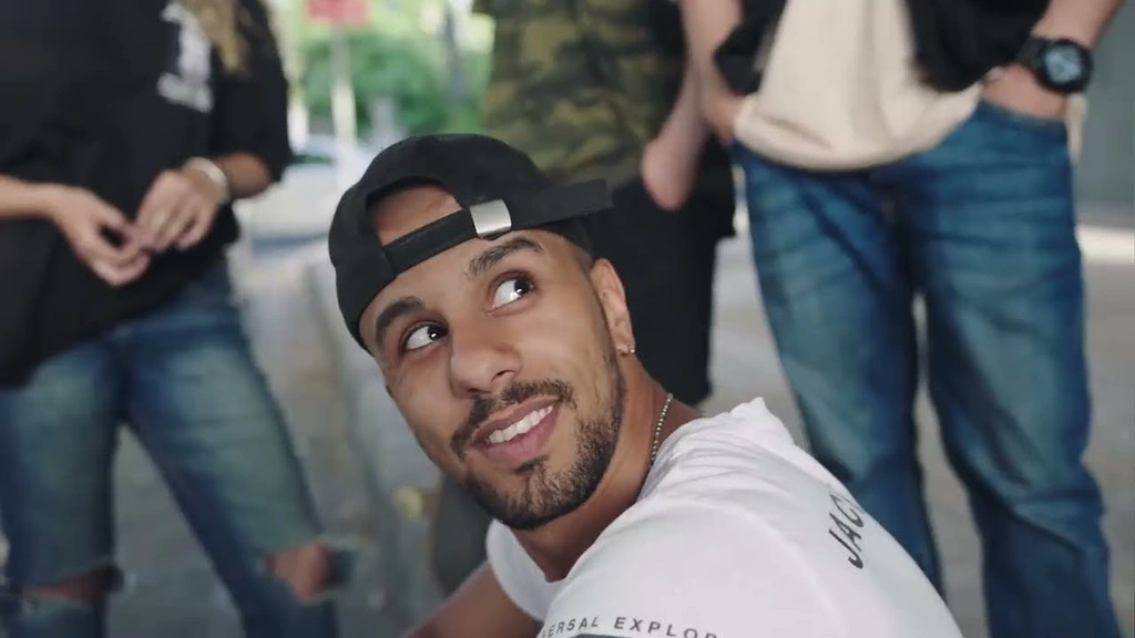 A performer in a backwards cap looks up from a group of friends.