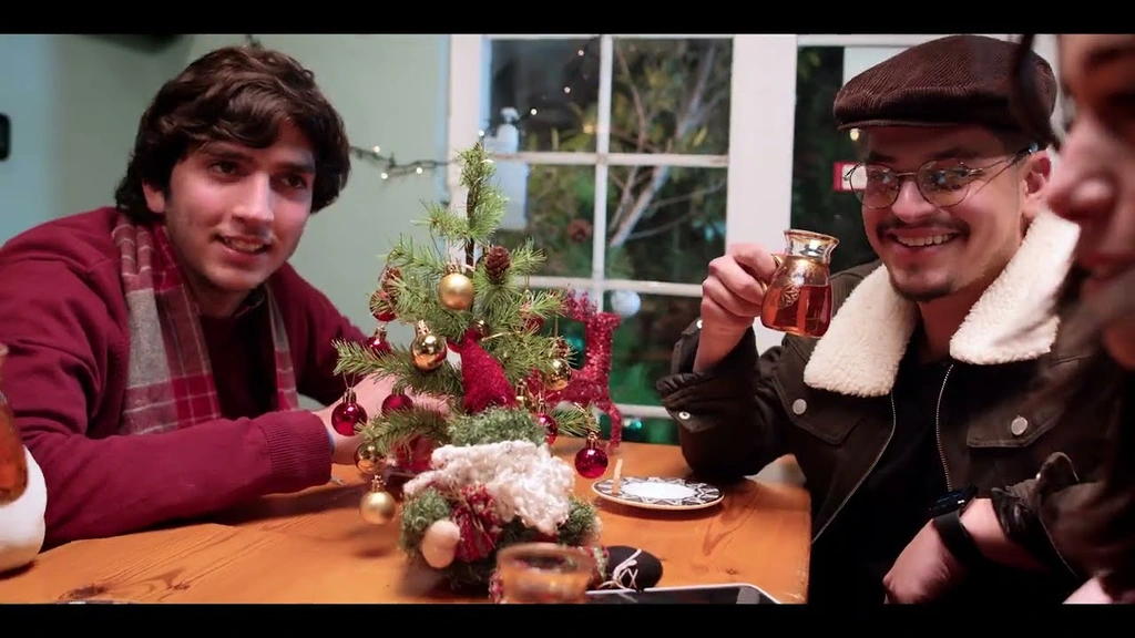 Friends sharing drinks around a café table decorated for Christmas.