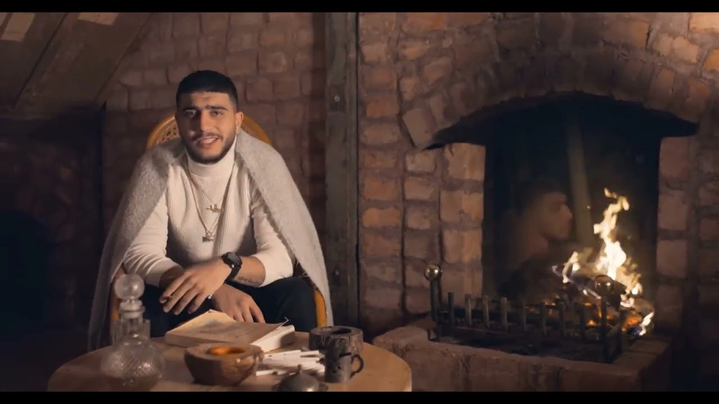 Salameh seated beside a stone fireplace in warm amber light.