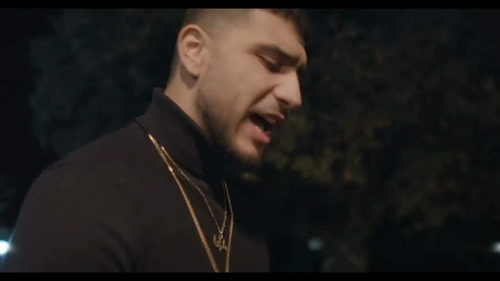 Salameh in a dark shirt and gold chains during an outdoor performance.