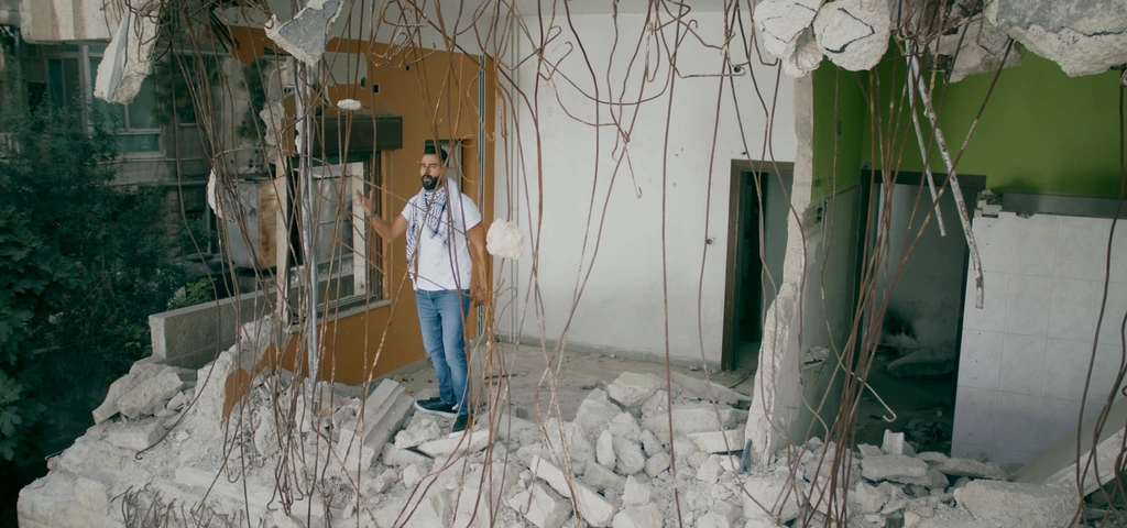 Toni Qattan stands among the architectural lines of the ruined-building set.