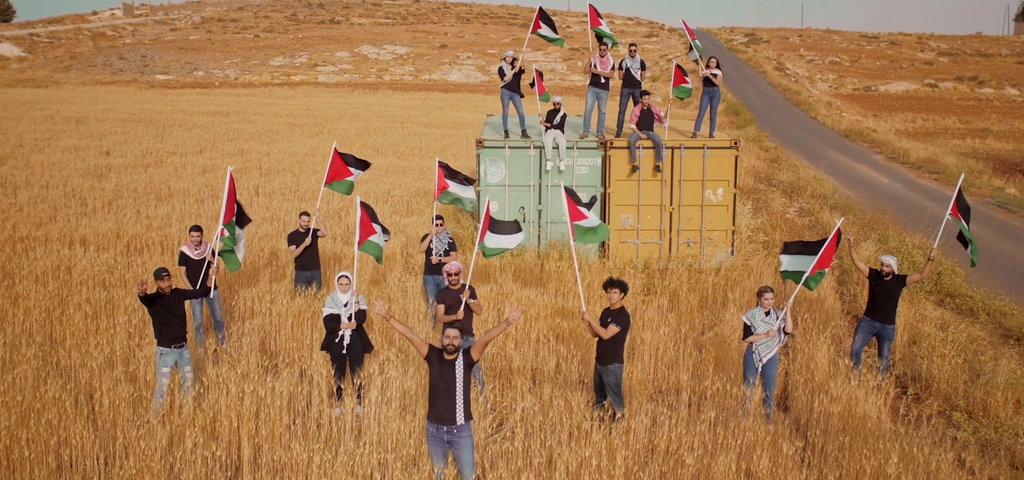 An elevated wide view shows the performers, flags and container stage in the field.