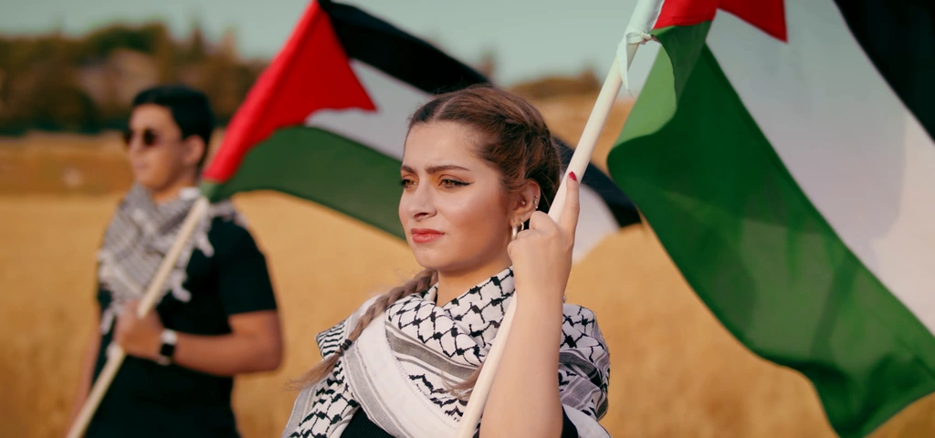 A close portrait of a woman holding a flag in the golden field.