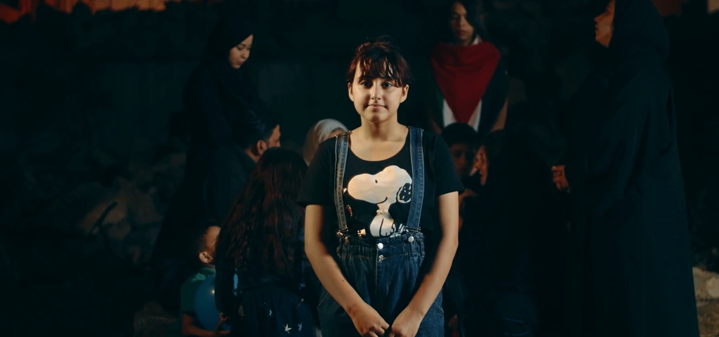 A young performer is framed by the soft warm light and darker group behind her.