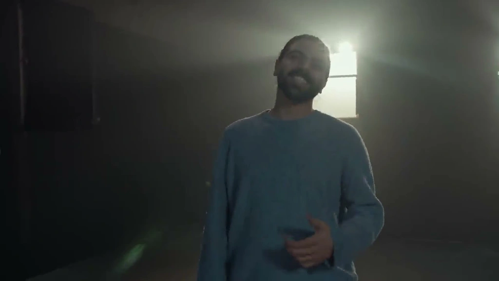 Alawar performing beneath a bright window in a hazy room.