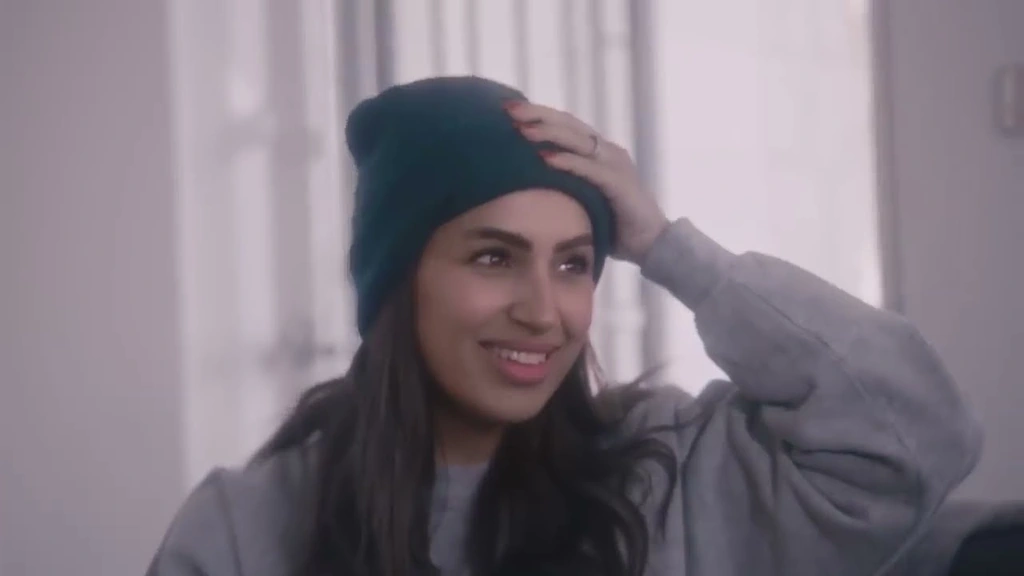 A woman in a dark beret smiling in soft window light.