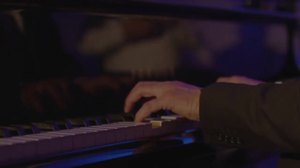 Close-up of a pianist’s hands and their reflections on the grand piano.