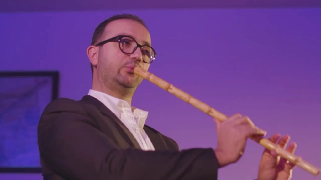 A close portrait of the woodwind player with the instrument angled across the frame.