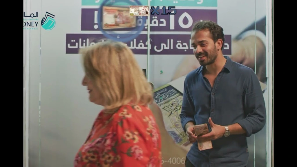 A man talking to a woman at a counter in the Money for Finance commercial.