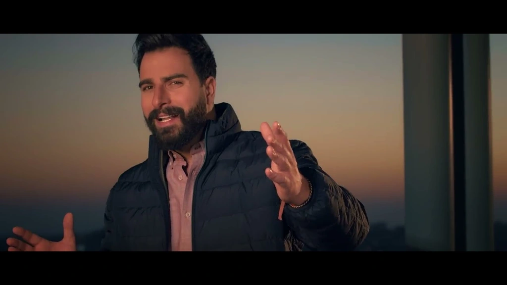 Toni Qattan performs beside a window with warm evening light behind him.