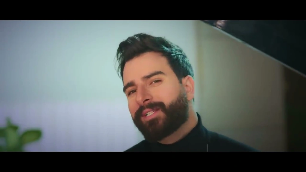 Toni Qattan in a black shirt, framed by a softly lit interior.