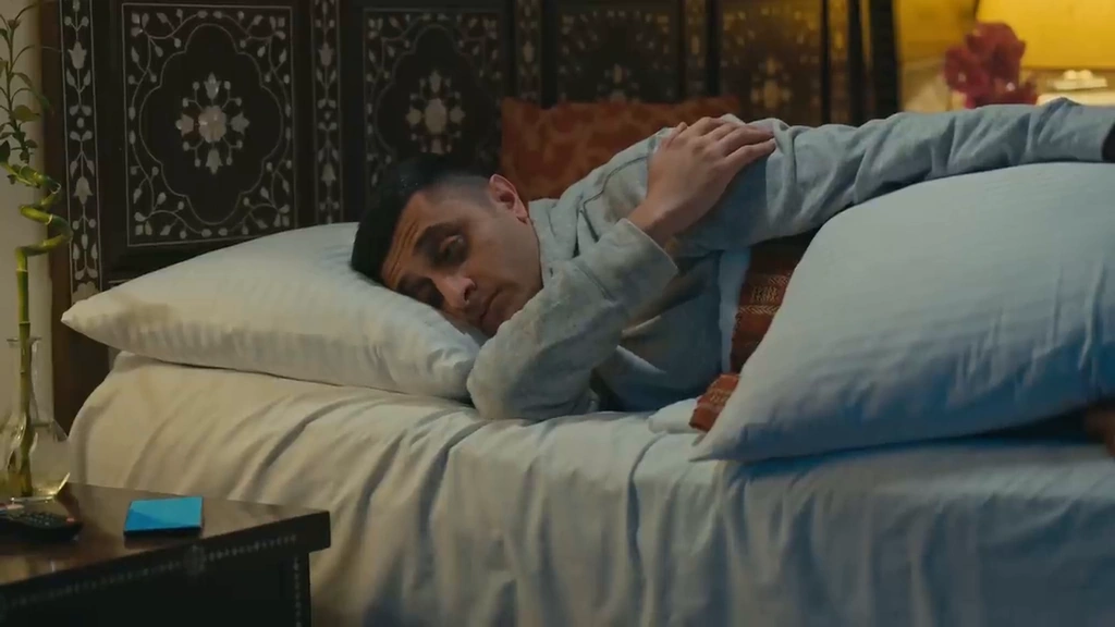 A man lies on a bed in a softly lit bedroom.