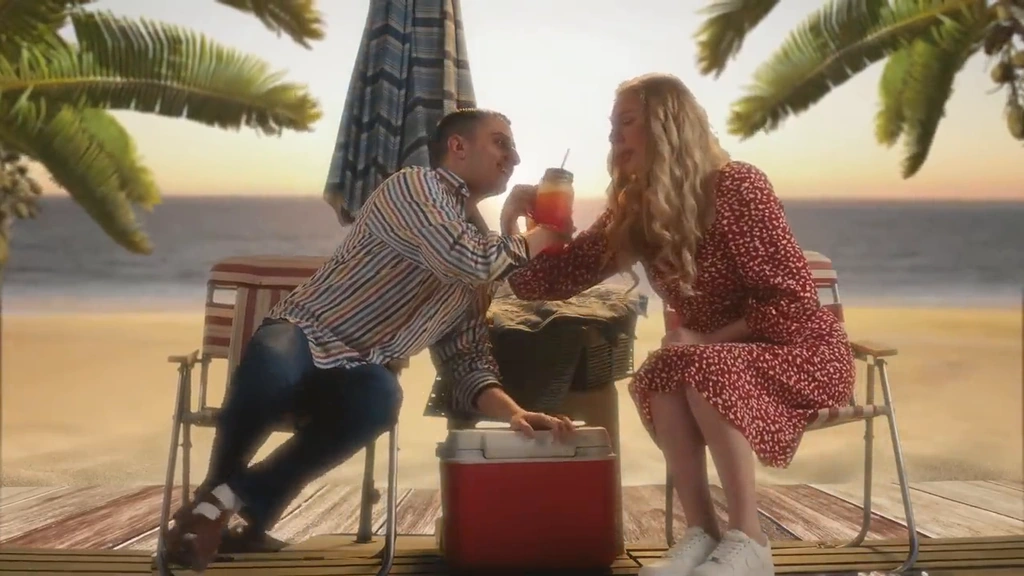 Two characters share a drink at a small table beneath palm trees in a warm tropical fantasy scene.