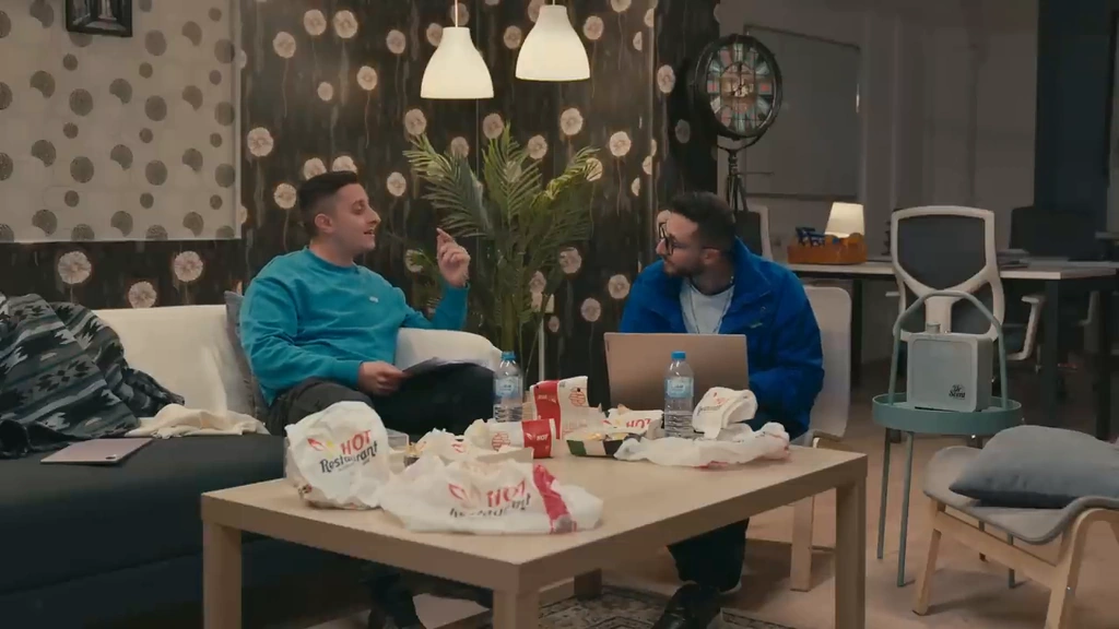 A wide conversation scene with two men on sofas in a patterned living-room set.