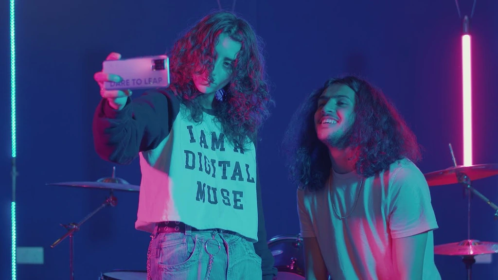 Two people taking a selfie in a neon-lit music studio.