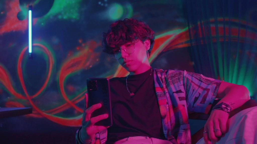 A man with a phone in a colourful neon-lit studio.