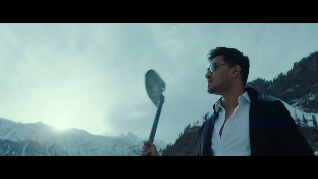 SPY — A man holding equipment against a snowy mountain landscape.