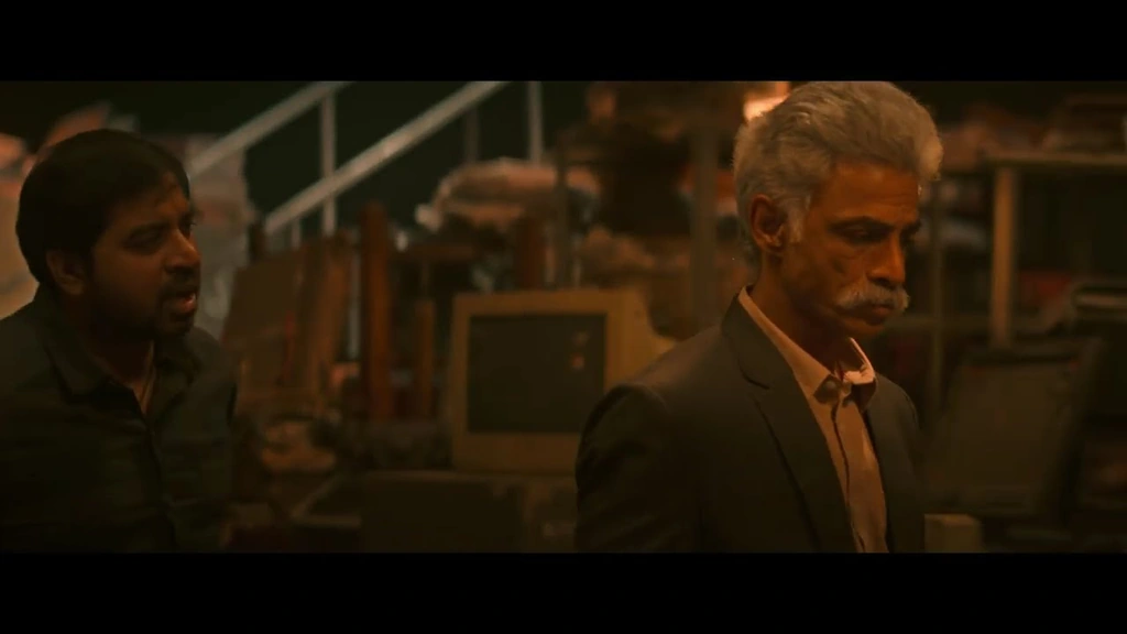Two men in a dim, warm-lit interior in the SPY teaser.
