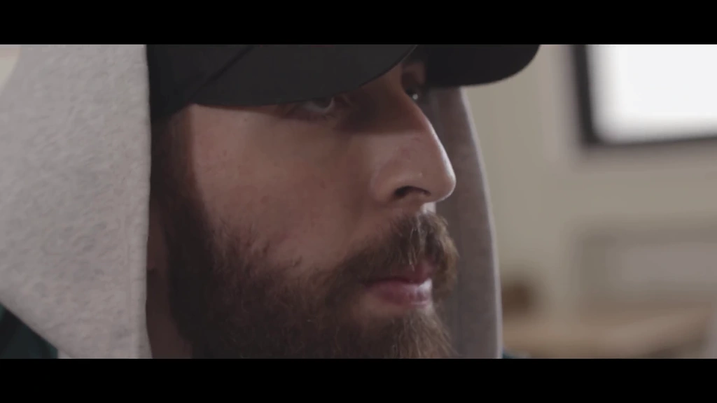 Profile close-up of llunr beneath the edge of his cap in the classroom sequence.