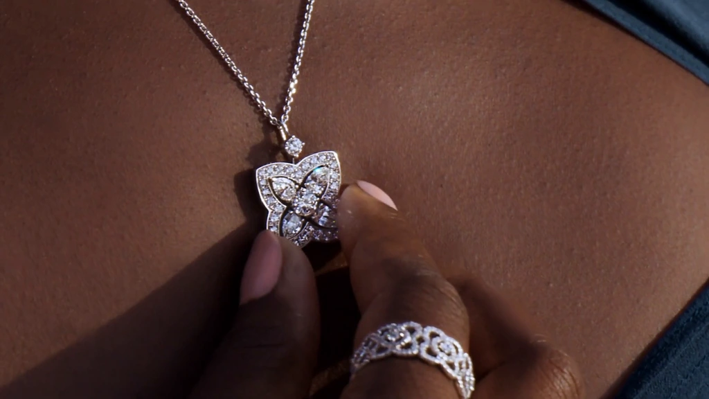 A close view of a diamond pendant and rings against a deep blue dress.