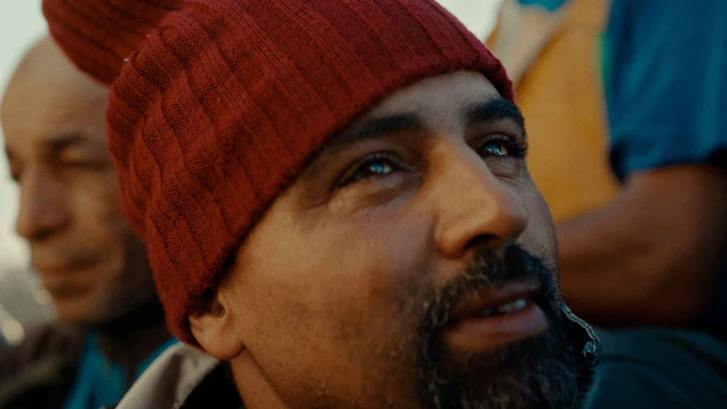 A man in a red knitted cap, framed closely among a group.
