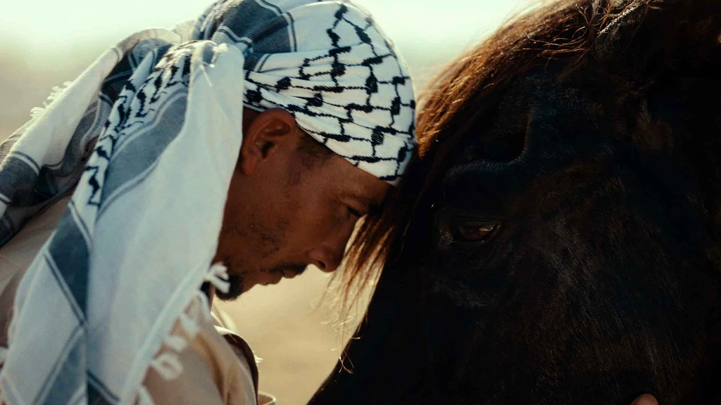 Two people bow their heads together in a close, sunlit portrait.