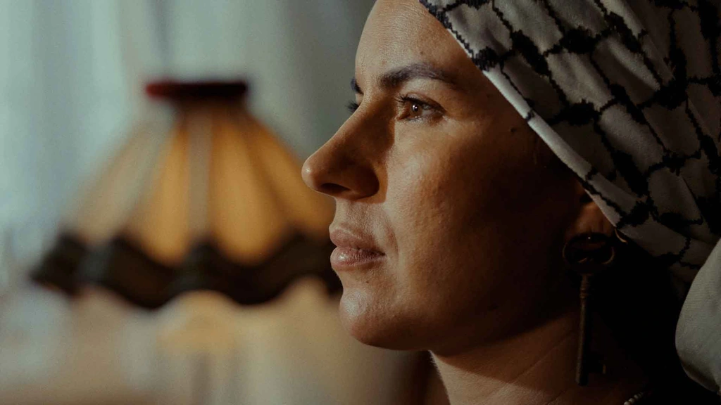 A close profile of a woman wearing a patterned headscarf in warm interior light.