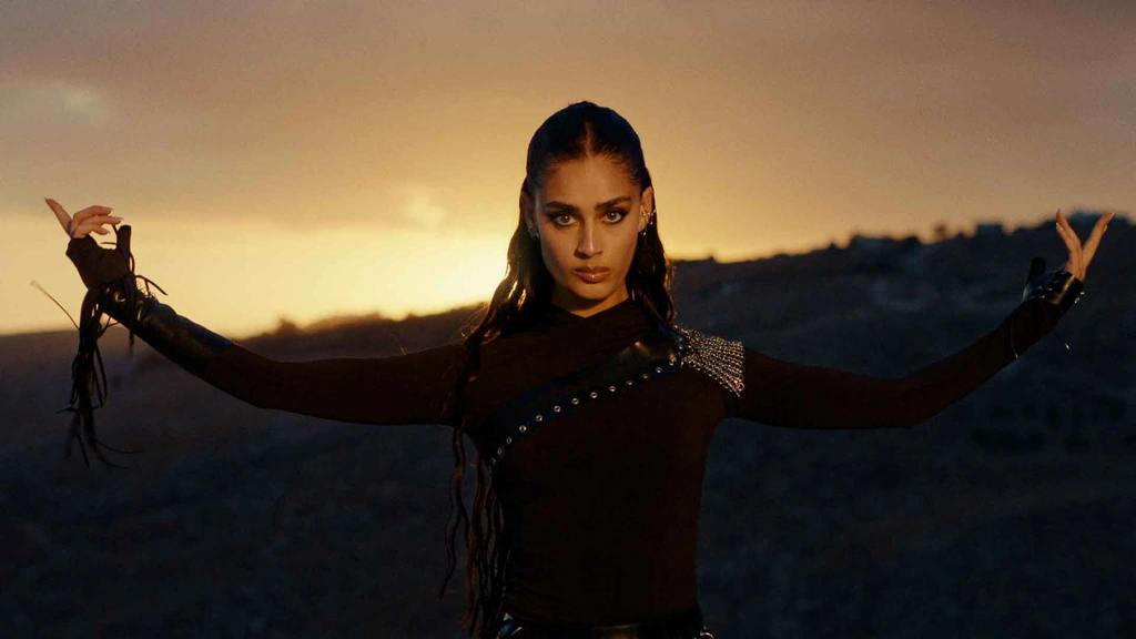Zeyne in black with her arms outstretched against a golden sunset.