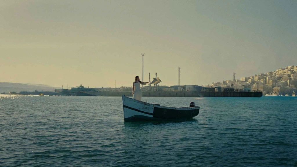 A small boat on blue water with a harbour and city in the distance.