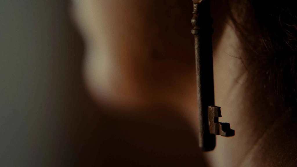 A key hanging against a softly lit, shallow-focus portrait.