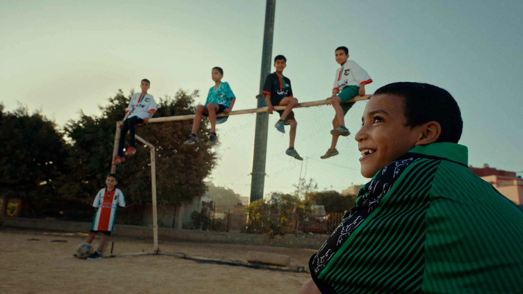 Young people gathered around a basketball hoop in afternoon light.