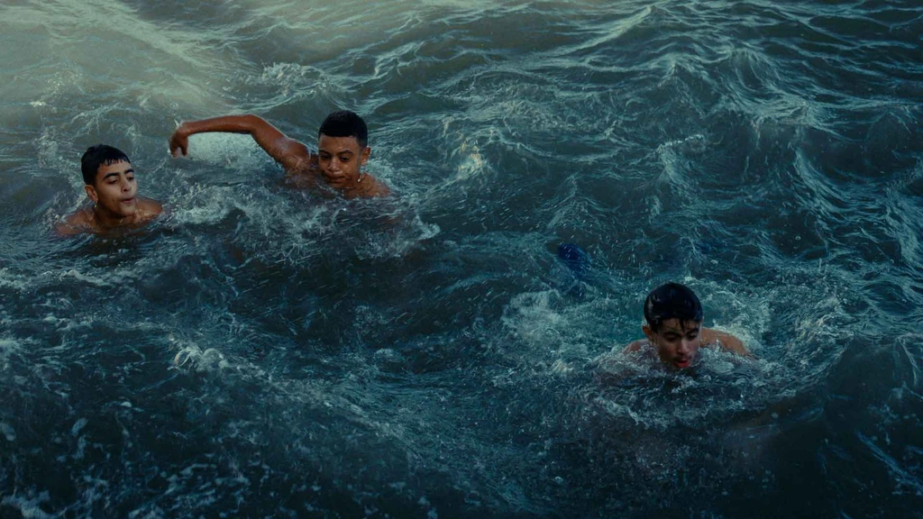 Three swimmers seen from above in textured blue sea water.