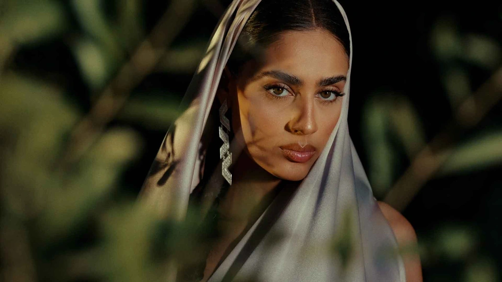 A close portrait of Zeyne, partially framed by soft green leaves.